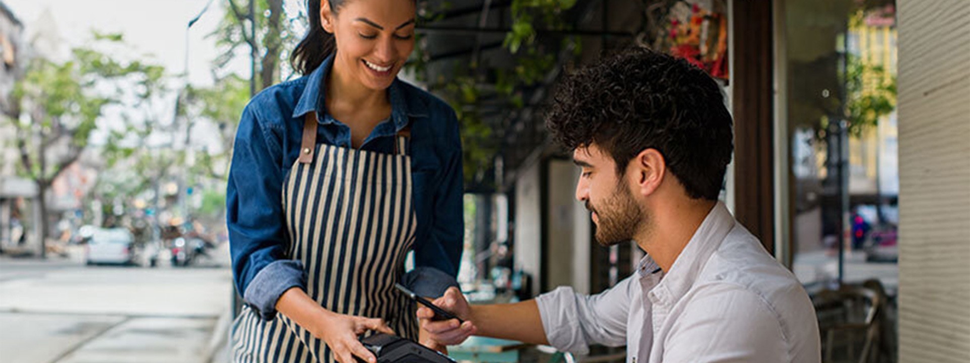 man making mobile payment in cafe