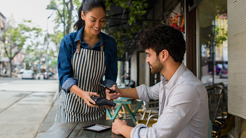 man making mobile payment in cafe