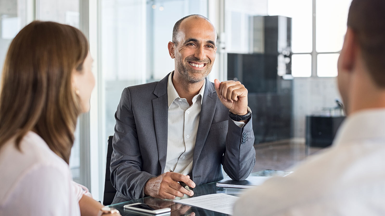 man smiling sat in a meeting 